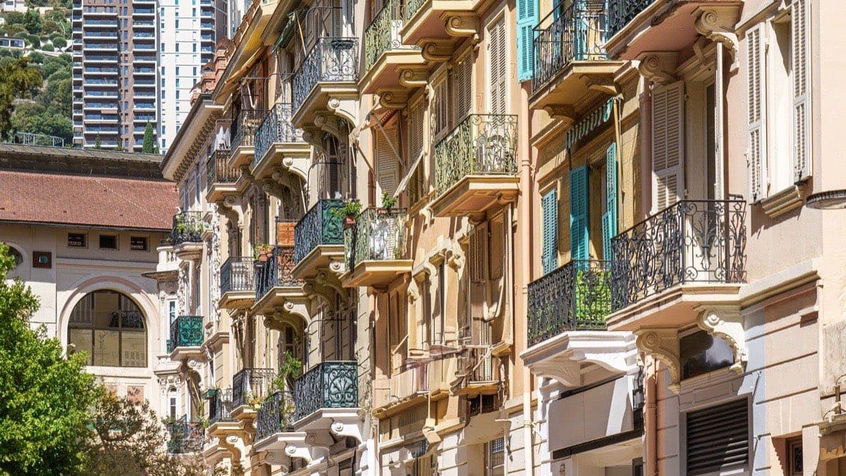 Enfilade de façades à Monaco, balcons en fer forgé, volets turquoise et pierre dorée