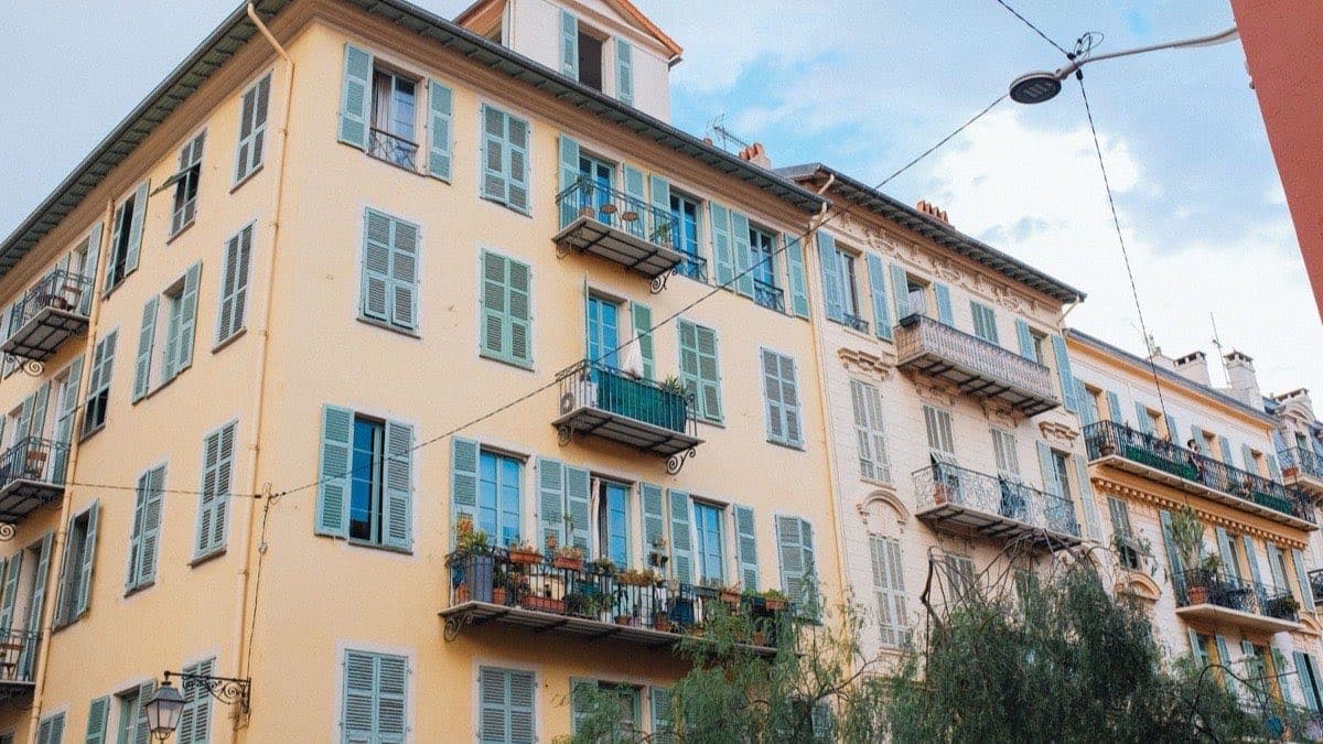 Immeuble d’habitation coloré, volets bois et balcons fleuris