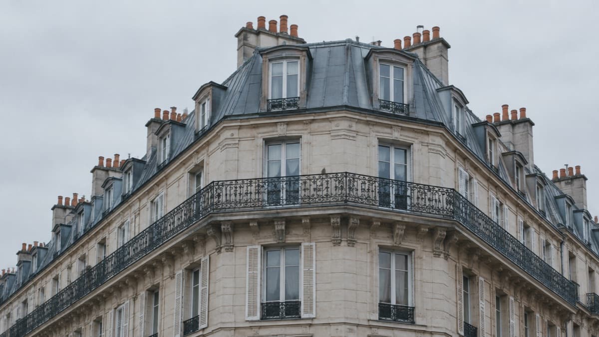 Immeuble d’angle haussmannien vu de la rue, toiture de zinc et alignement de souches de cheminées