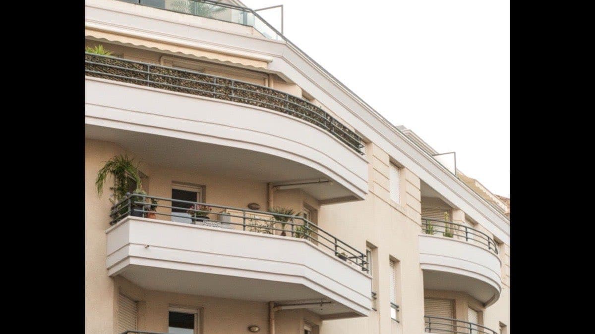 Façade d’un immeuble résidentiel d’Antibes, balcons arrondis et stores de toile, pierre crème